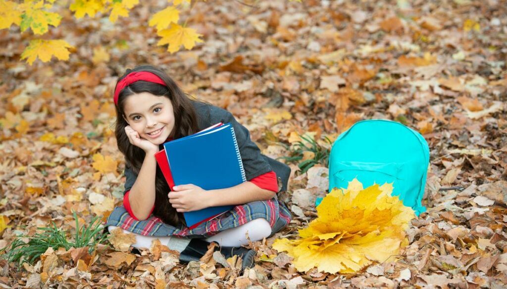 Daycare child with autumn leaves and books