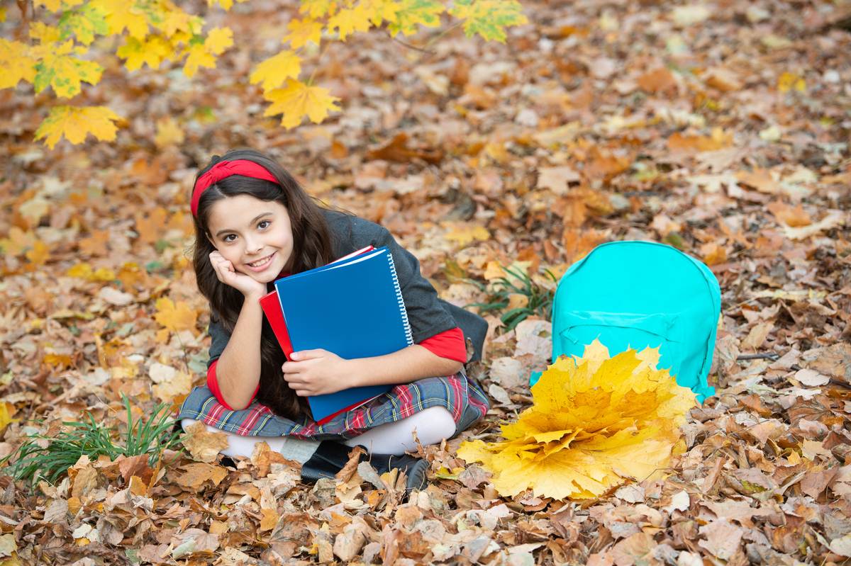 Daycare child with autumn leaves and books Daycare child with autumn leaves and books