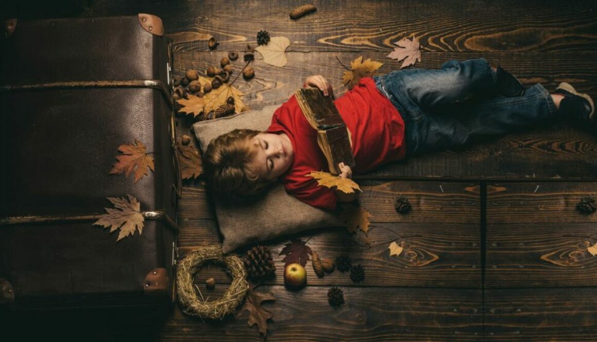 Kid playing in autumn and reading a book
