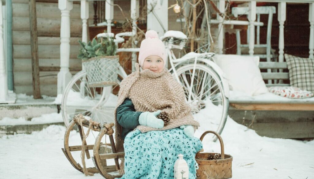 Cute little girl sitting on a sled in the winter