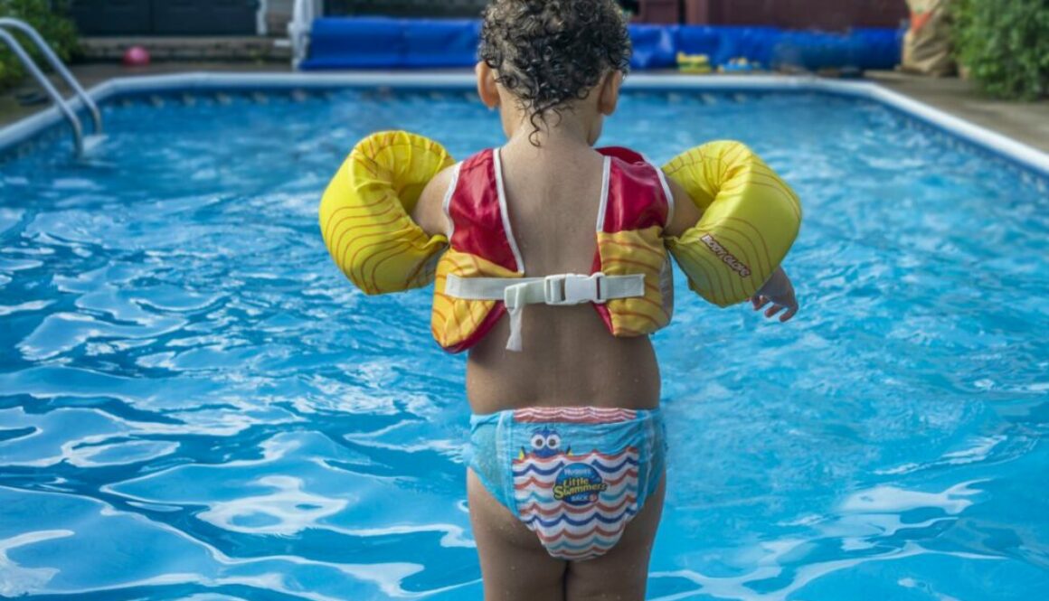 Daycare baby in safety gear swimming in the pool