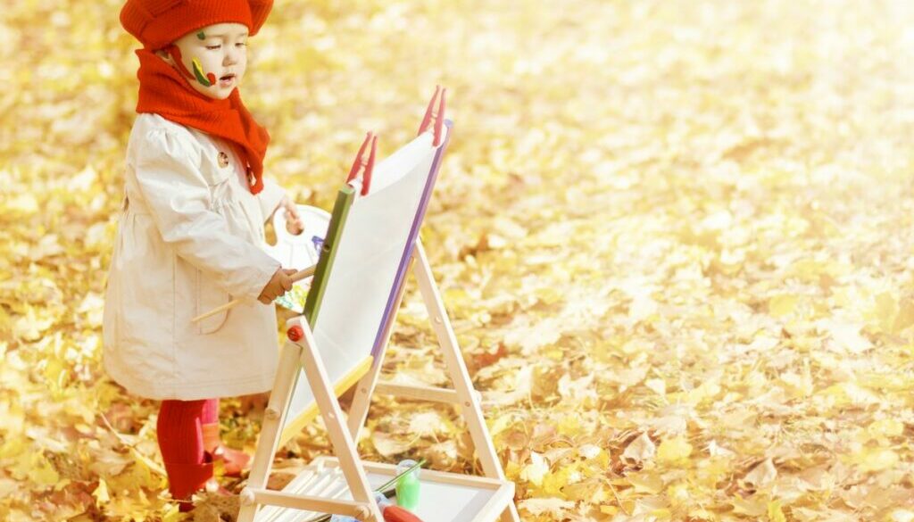Daycare baby painting on yellow fall leaves