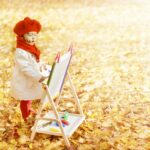 Daycare baby painting on yellow fall leaves