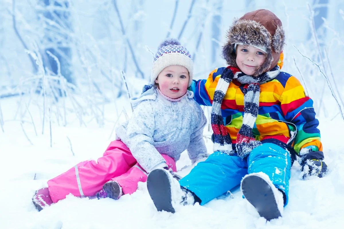 Children playing in winter hat in snow forest